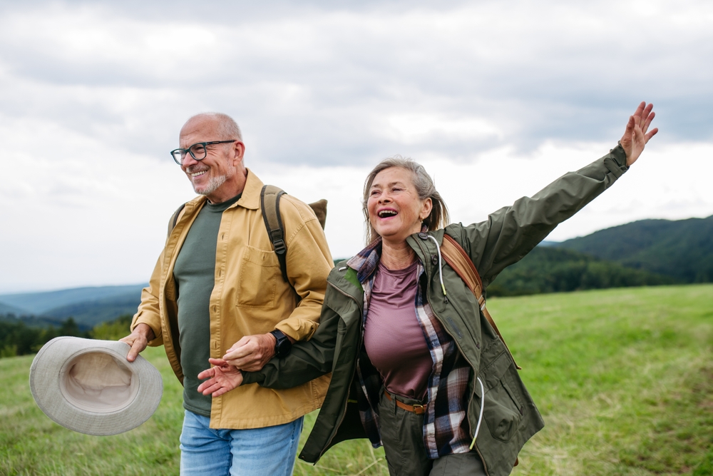 Senior couple hiking joyfully on a green hillside